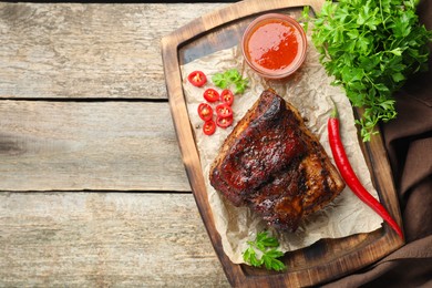 Photo of Piece of baked pork belly served with sauce and chili pepper on wooden table, top view. Space for text