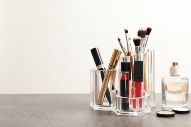 Photo of Lipstick holder with different makeup products on table against white background. Space for text