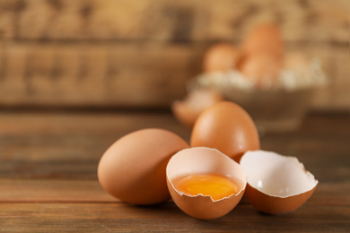 Photo of Raw brown chicken eggs on wooden table. Space for text