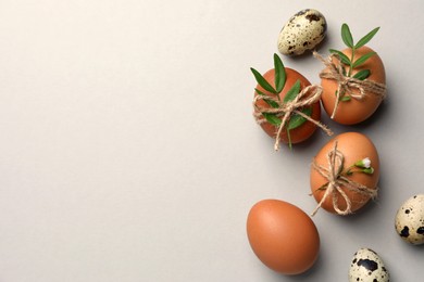 Happy Easter. Chicken and quail eggs with natural decor on light grey background, flat lay. Space for text