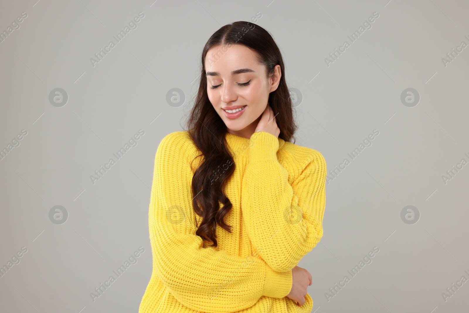 Photo of Beautiful young woman in stylish warm sweater on grey background