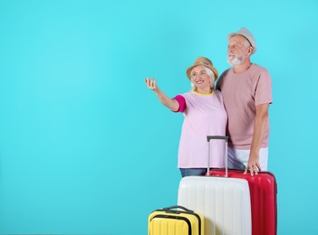 Photo of Senior couple with suitcases on color background. Space for text