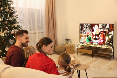 Photo of Happy family spending time together near TV in cosy room. Christmas atmosphere