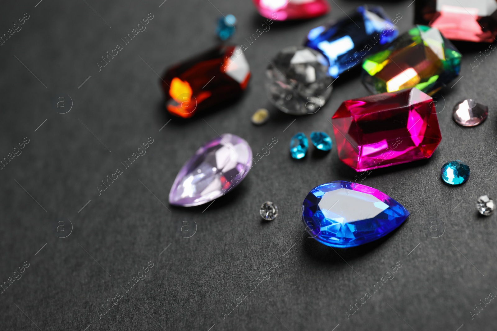 Photo of Different beautiful gemstones on black background. Space for text