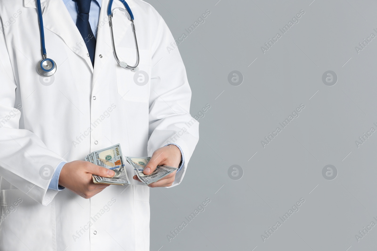 Photo of Doctor with bribe on grey background, closeup. Corruption in medicine