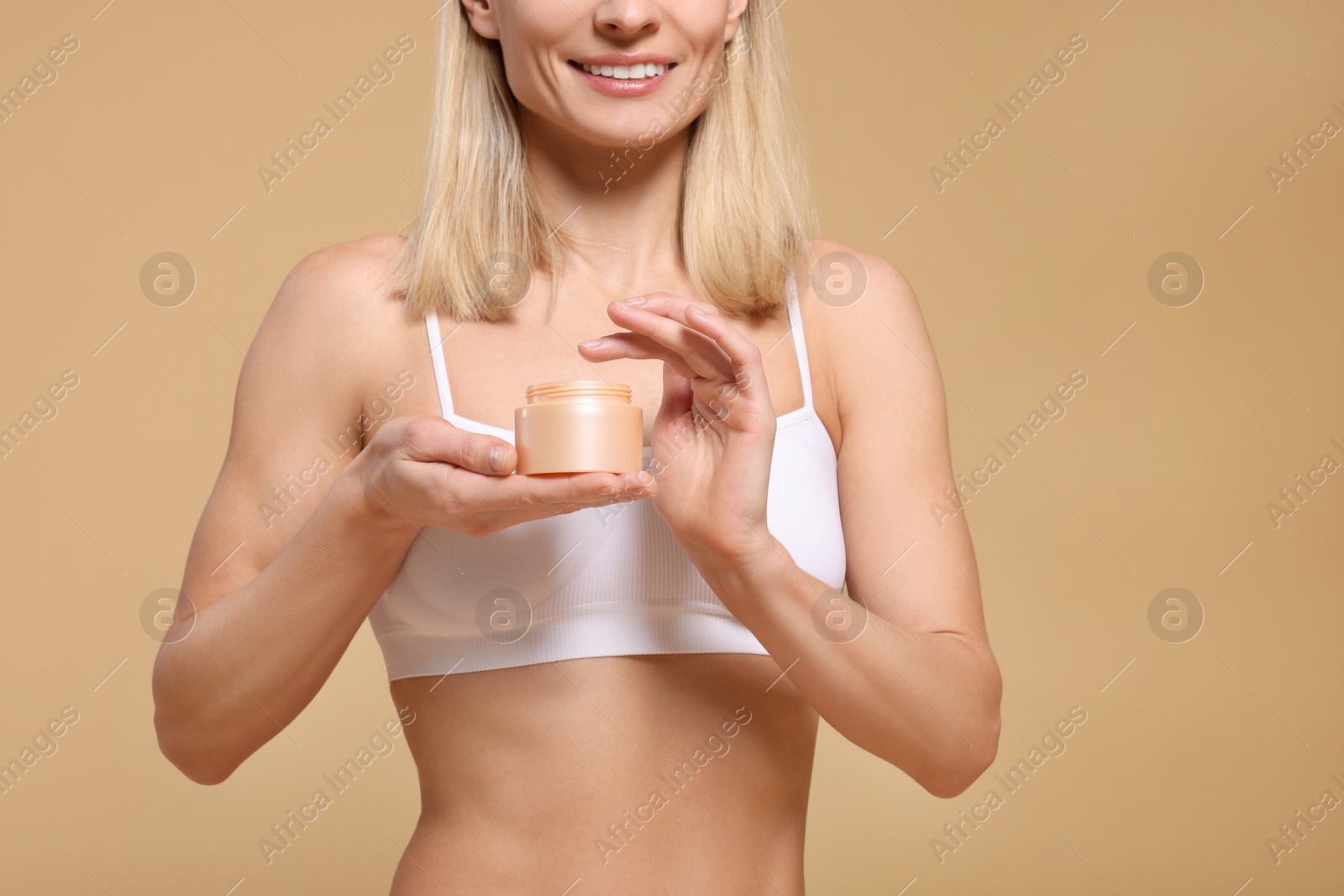 Photo of Woman with jar of body cream on beige background, closeup. Space for text