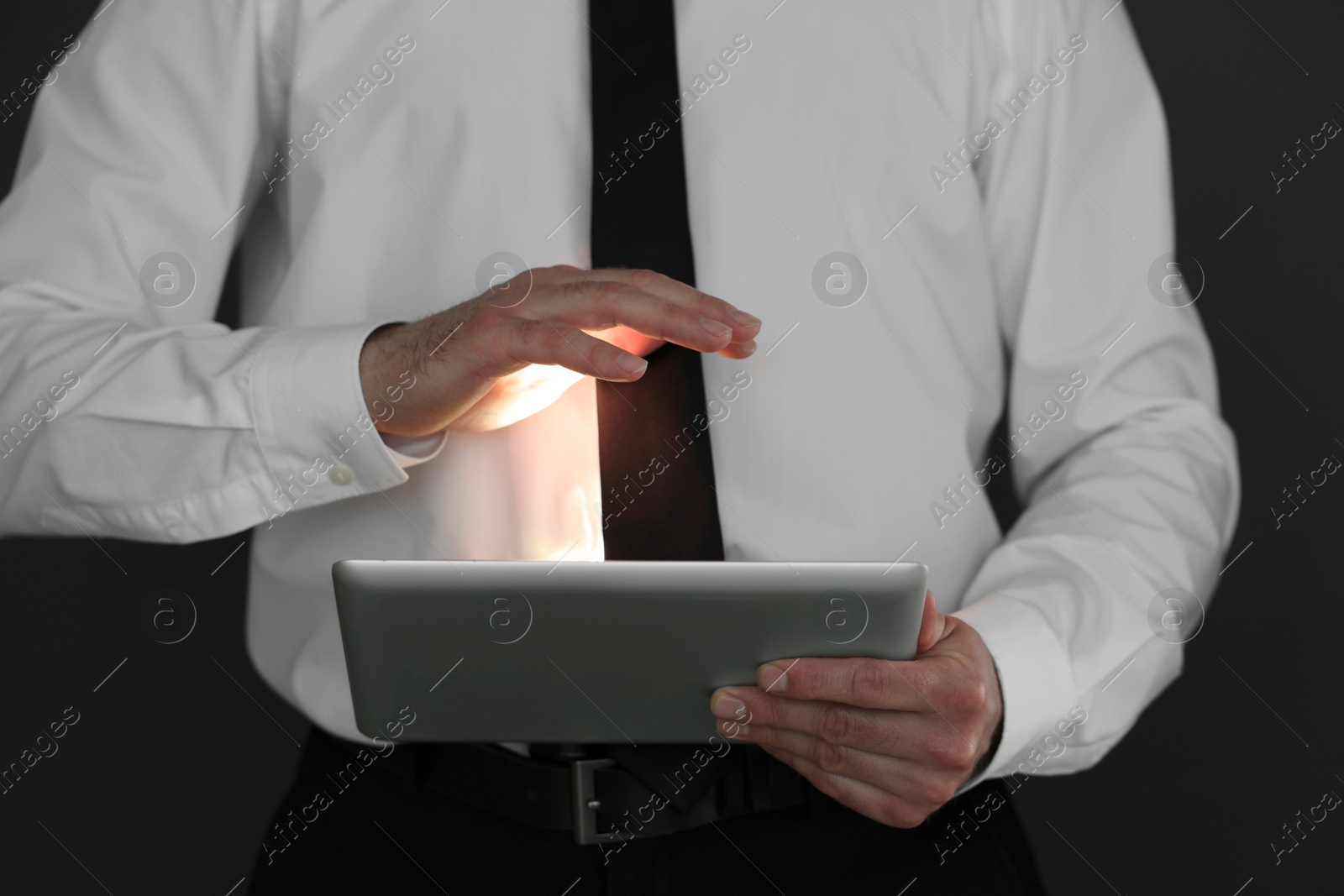 Photo of Closeup view of businessman using new tablet on black background