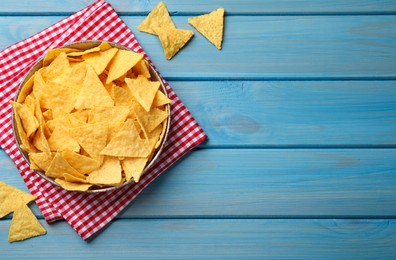 Photo of Tortilla chips (nachos) on light blue wooden table, flat lay. Space for text