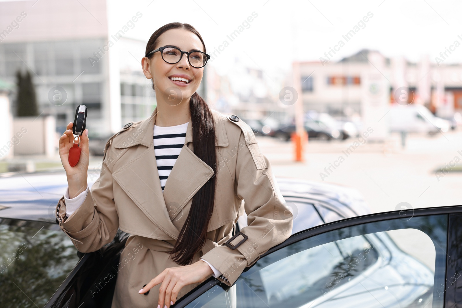 Photo of Woman holding car flip key near her vehicle outdoors