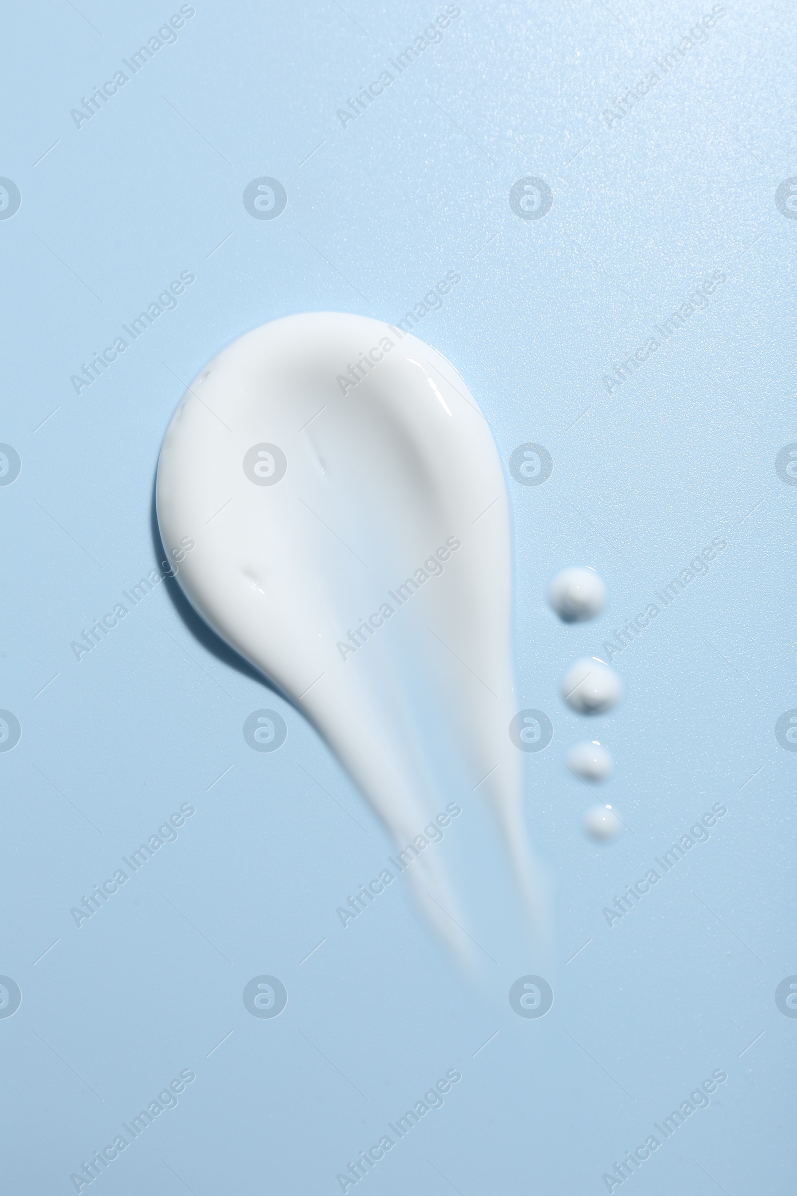 Photo of Sample of face cream on light blue background, top view