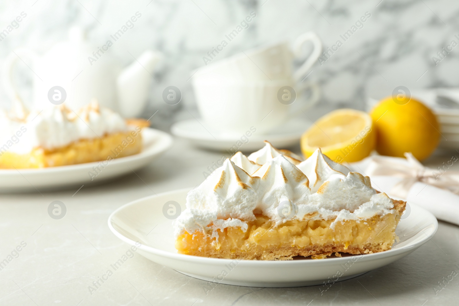 Photo of Plate with piece of delicious lemon meringue pie on light table