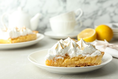 Photo of Plate with piece of delicious lemon meringue pie on light table