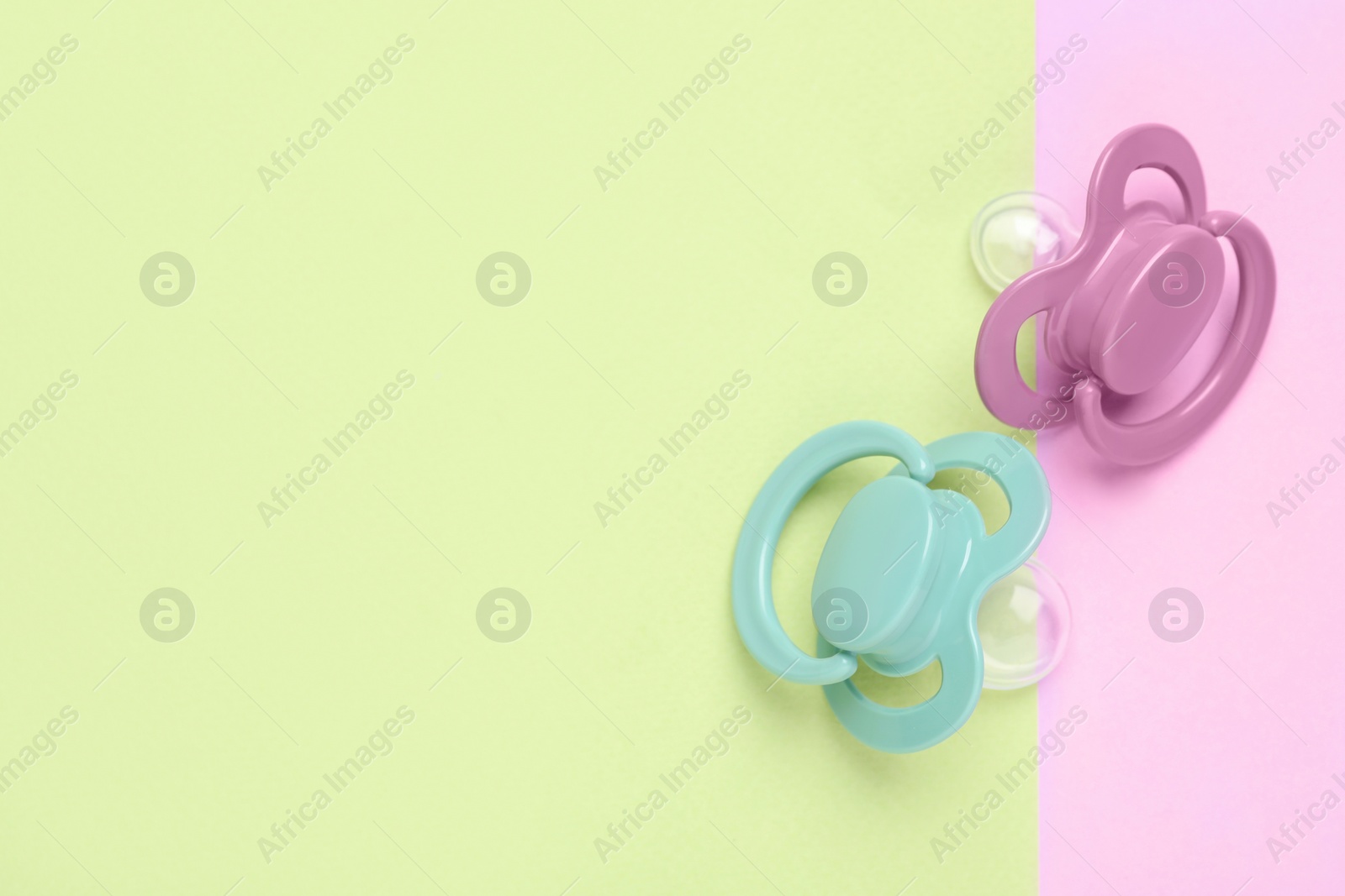 Photo of Baby pacifiers on color background, top view. Space for text