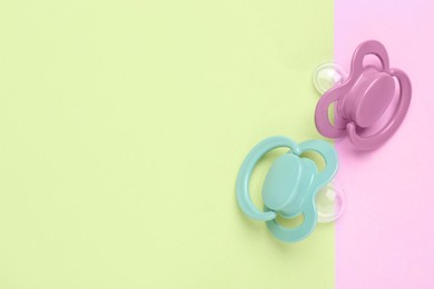 Photo of Baby pacifiers on color background, top view. Space for text