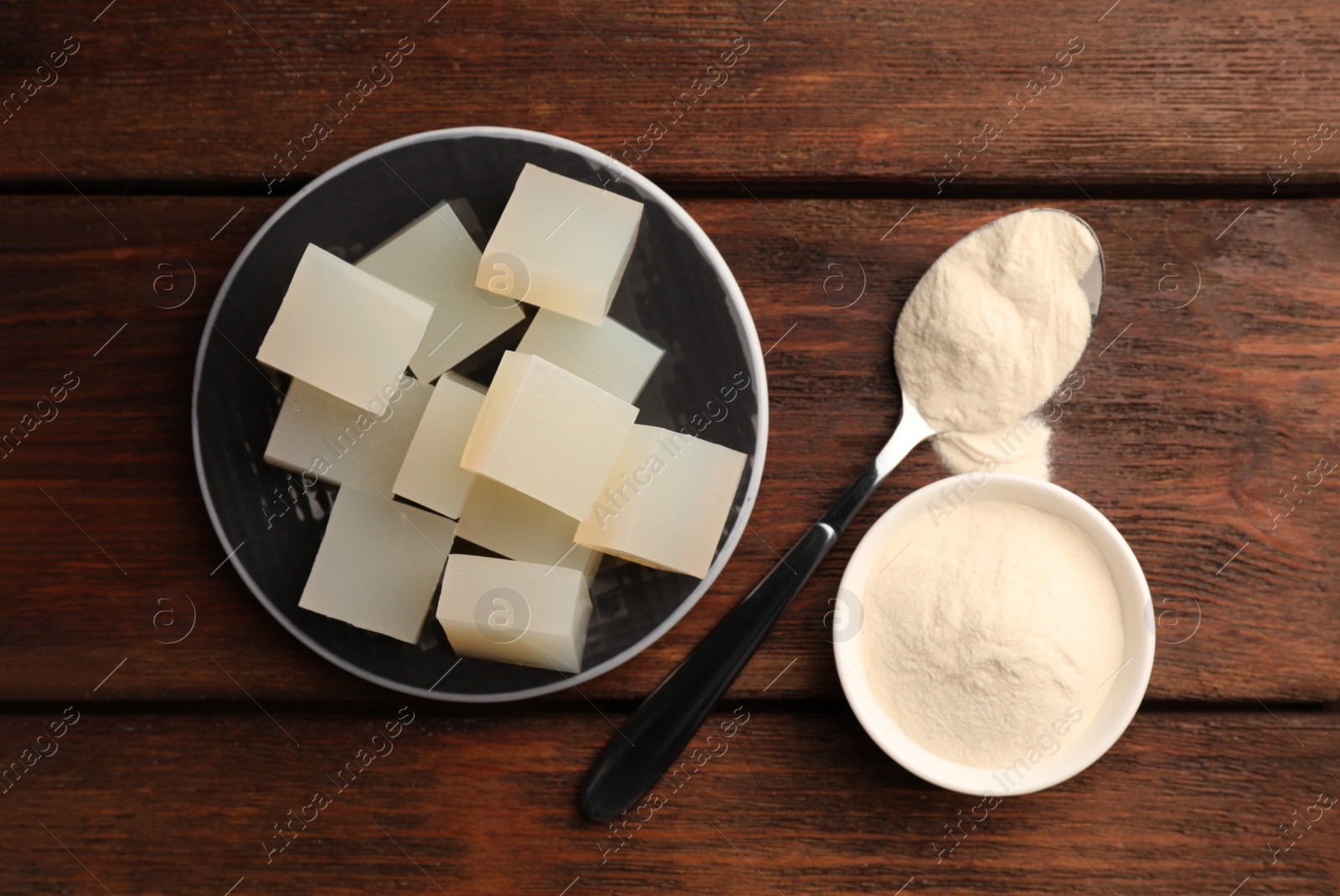 Photo of Agar-agar jelly cubes and powder on wooden table, flat lay