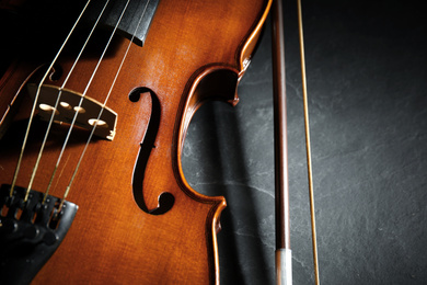 Photo of Classic violin and bow on stone table, closeup