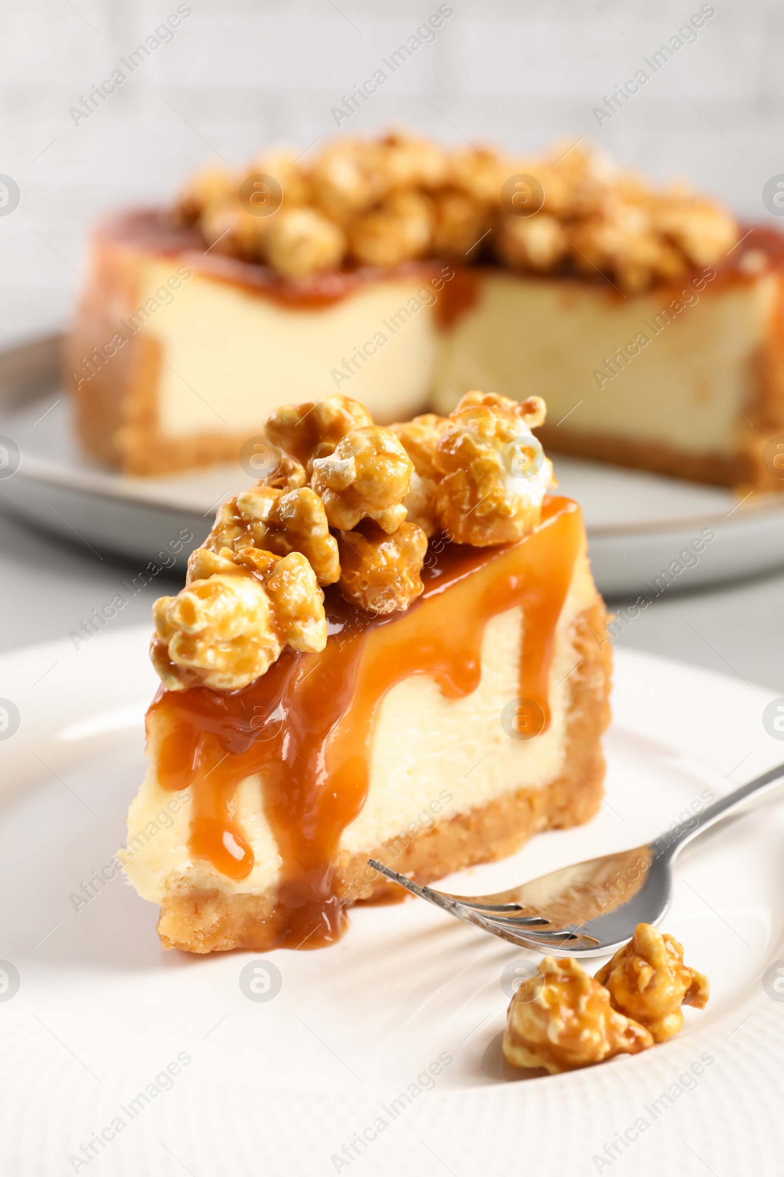 Photo of Piece of delicious caramel cheesecake with popcorn on plate, closeup