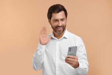 Photo of Handsome bearded man using smartphone on beige background