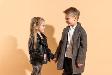 Photo of Fashion concept. Stylish children posing on pale orange background