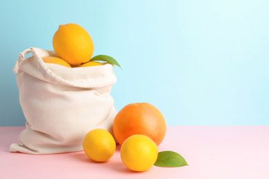 Photo of Cotton eco bag with citrus fruits on color background. Space for text