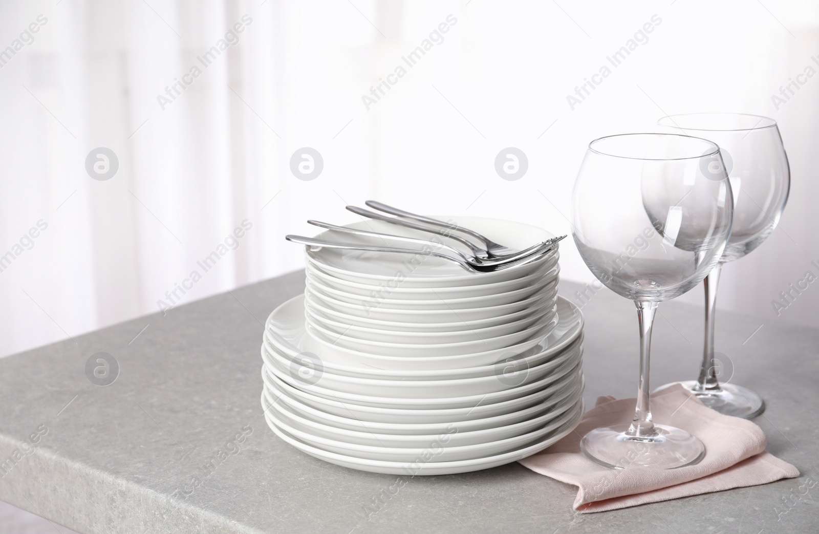 Photo of Set of clean dishes on table against blurred background. Space for text