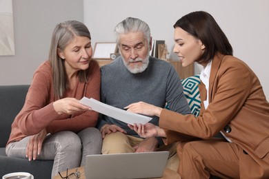 Insurance agent consulting elderly couple about pension plan in room