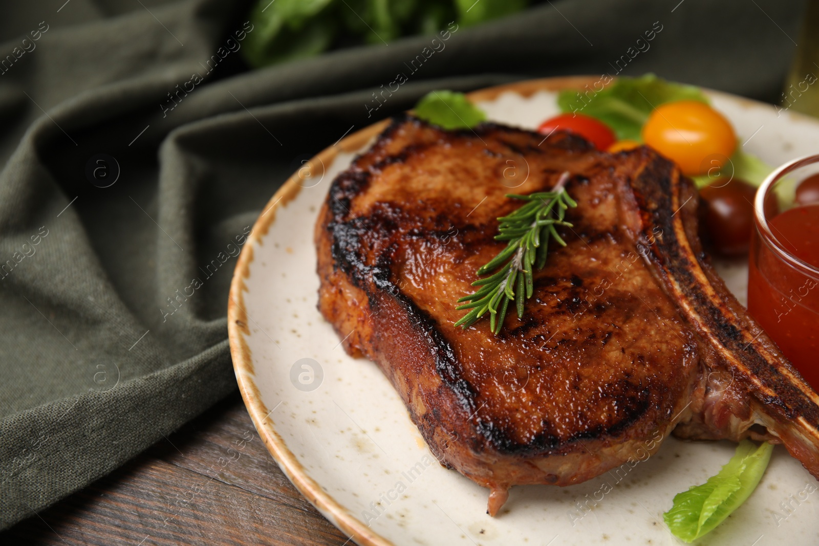 Photo of Tasty grilled meat, rosemary and marinade on wooden table, closeup