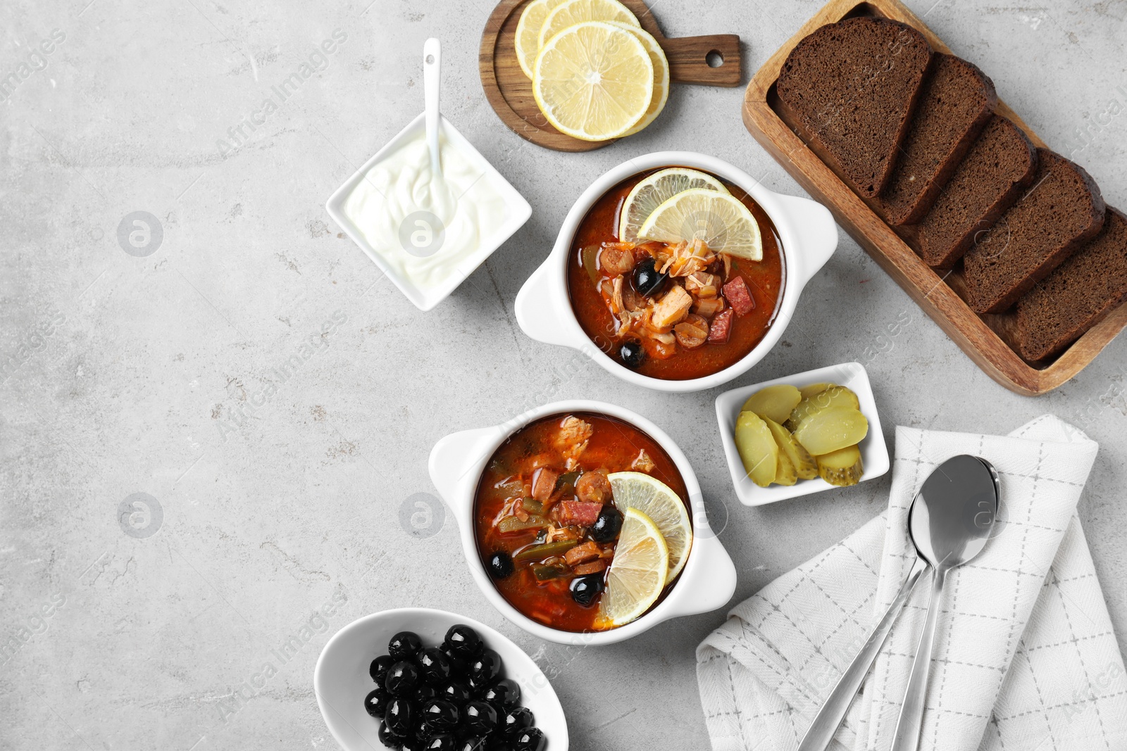 Photo of Meat solyanka soup with sausages, olives and vegetables served on white textured table, flat lay. Space for text