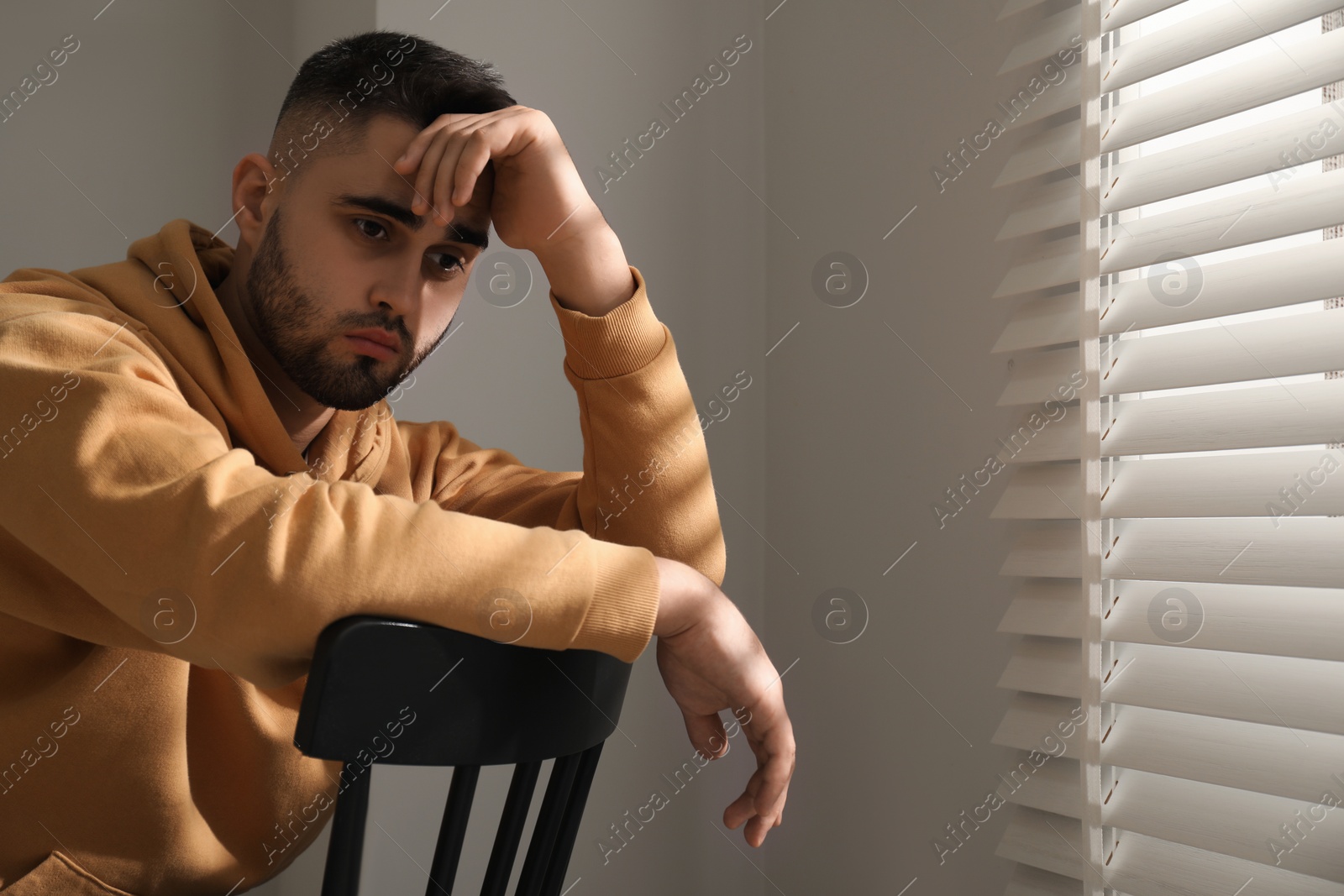 Photo of Sad man sitting on chair near window. Space for text