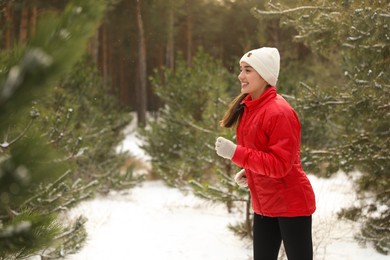 Happy woman running in winter forest. Outdoors sports exercises