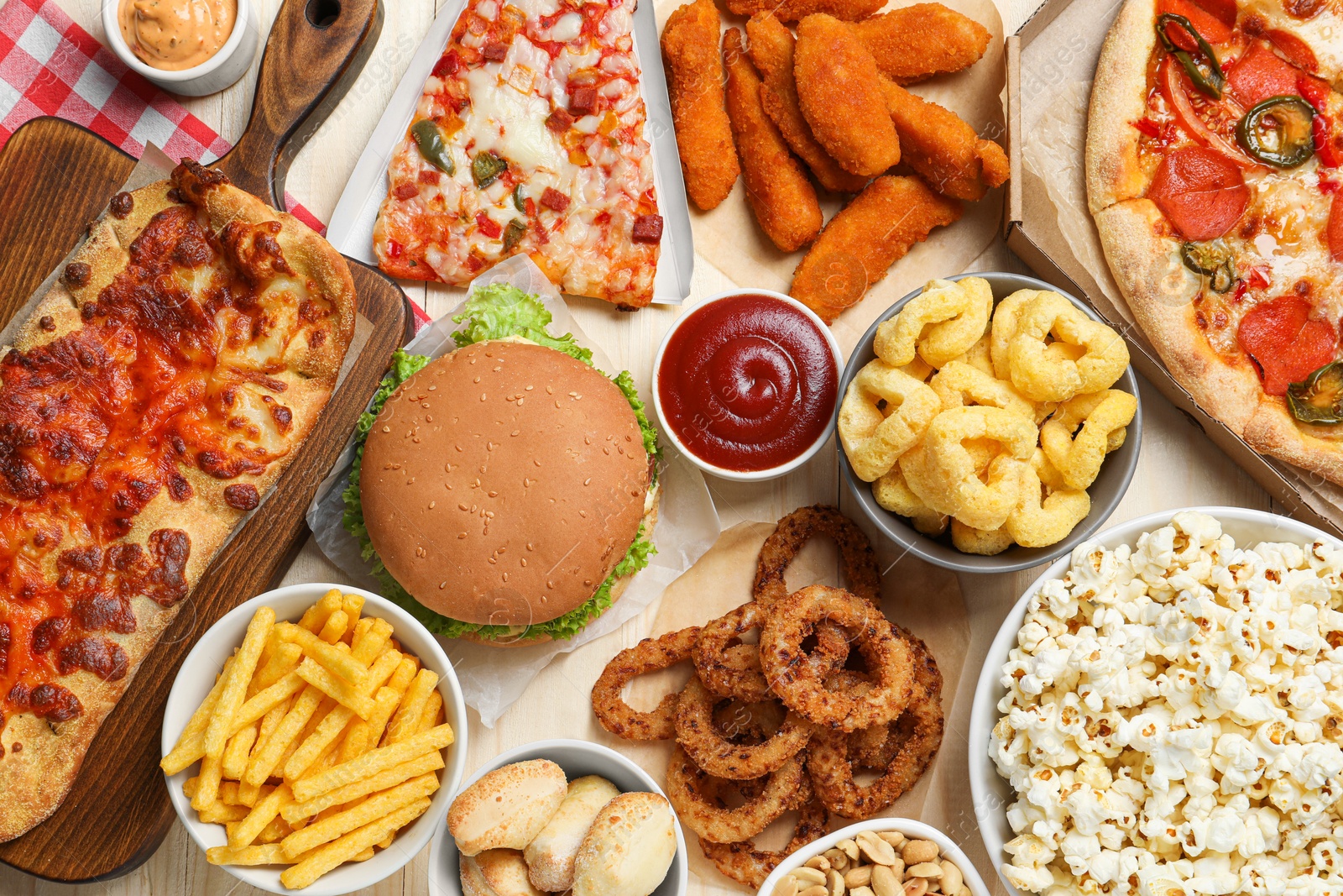 Photo of Pizza, chicken nuggets and other fast food on wooden table, flat lay