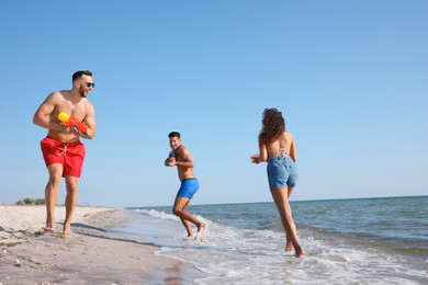 Friends with water guns having fun on beach