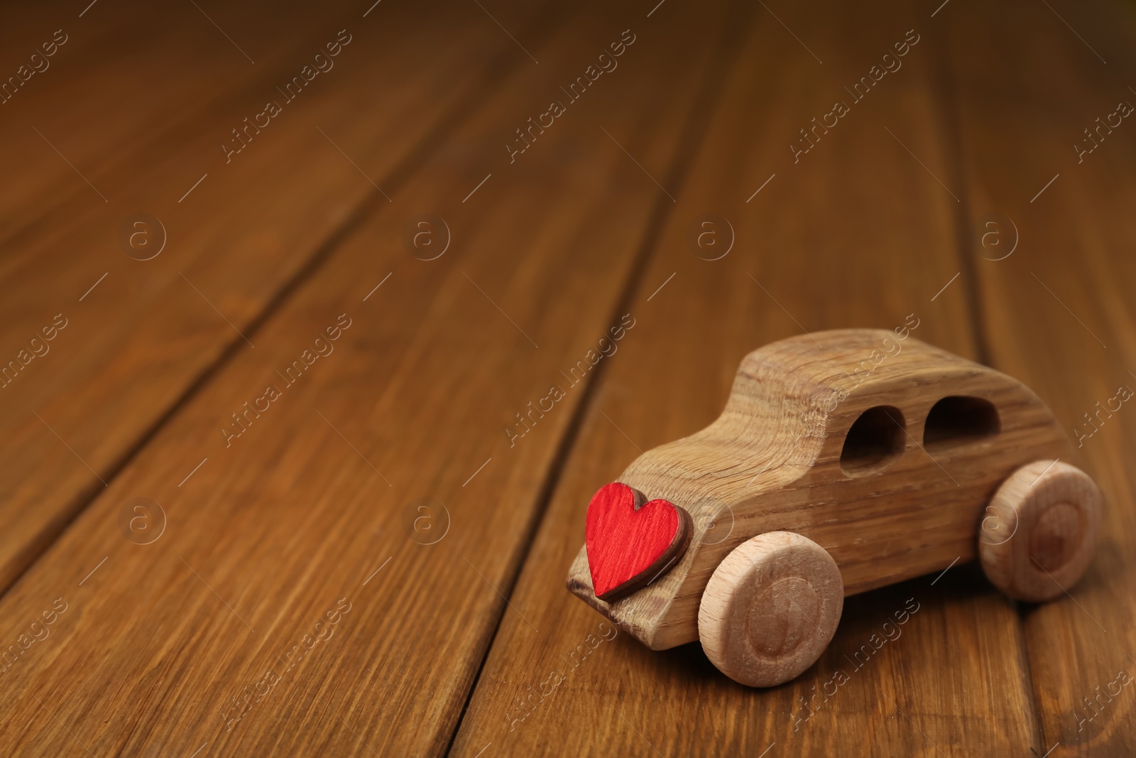 Photo of Wooden toy car with decorative heart on table, space for text. Happy Valentine's Day