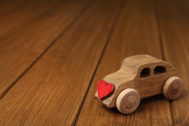 Wooden toy car with decorative heart on table, space for text. Happy Valentine's Day