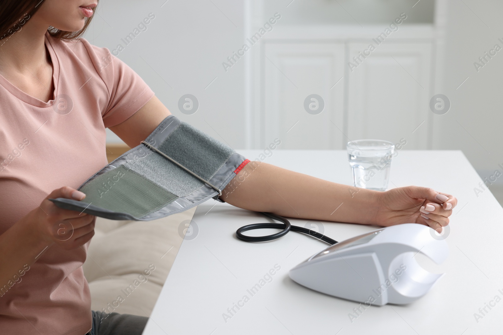 Photo of Woman measuring blood pressure with tonometer indoors, closeup
