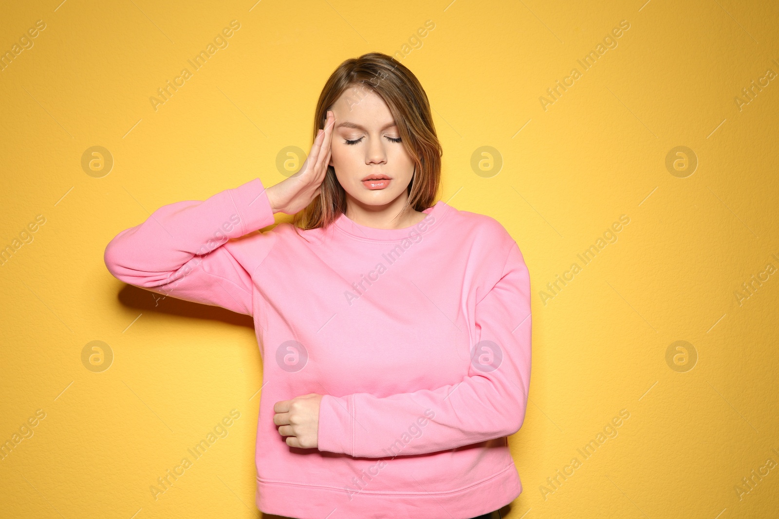 Photo of Young woman suffering from headache on color background