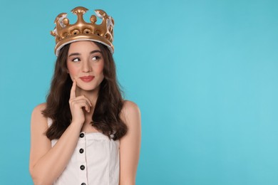 Photo of Beautiful young woman with inflatable crown on light blue background, space for text