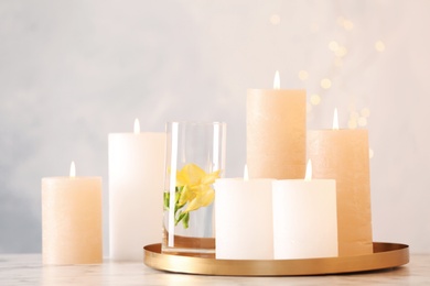 Photo of Composition with burning candles on table against light background