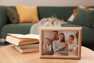 Photo of Framed family photo and books on wooden table indoors