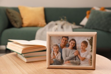 Framed family photo and books on wooden table indoors