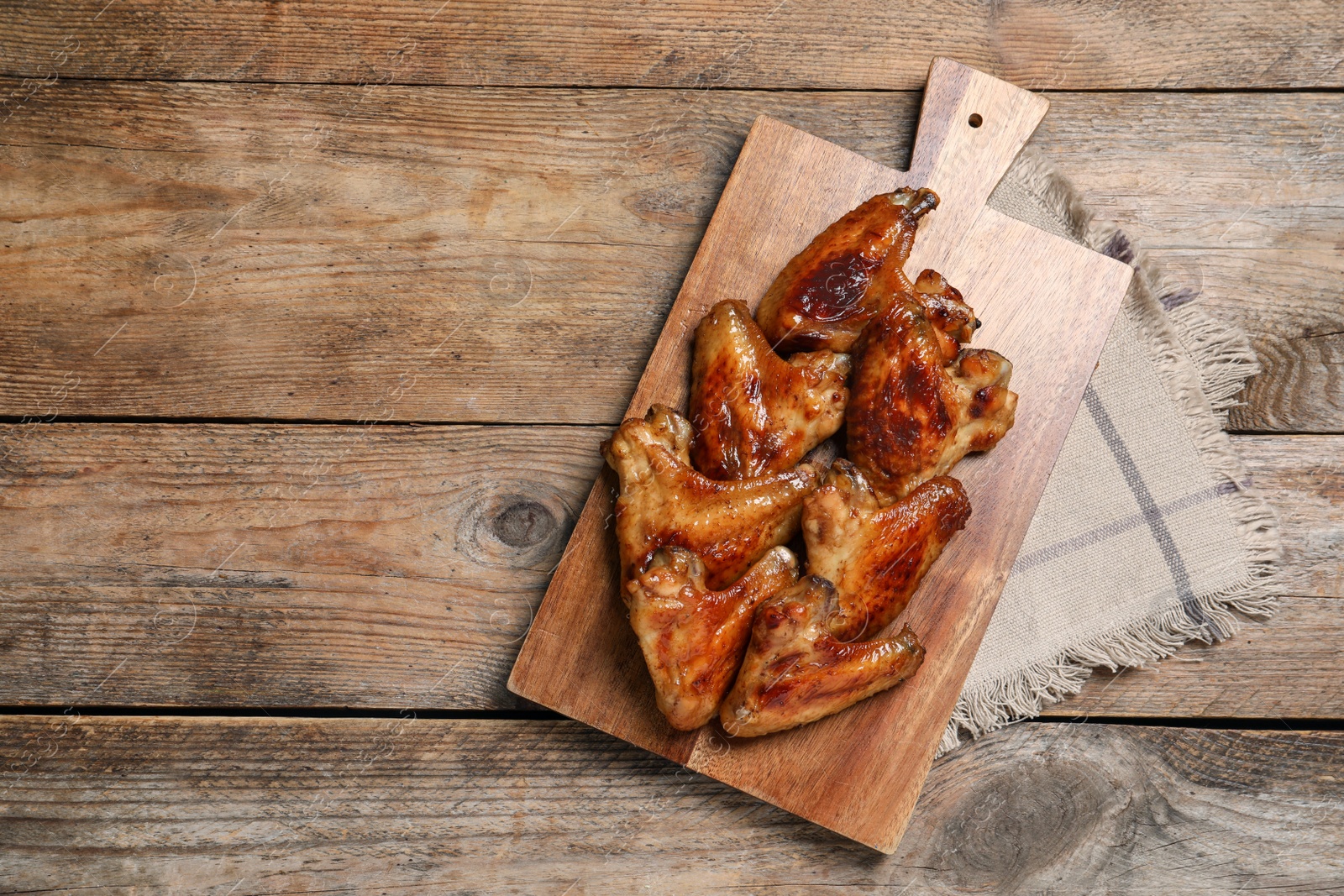 Photo of Board with delicious fried chicken wings on wooden table, top view. Space for text