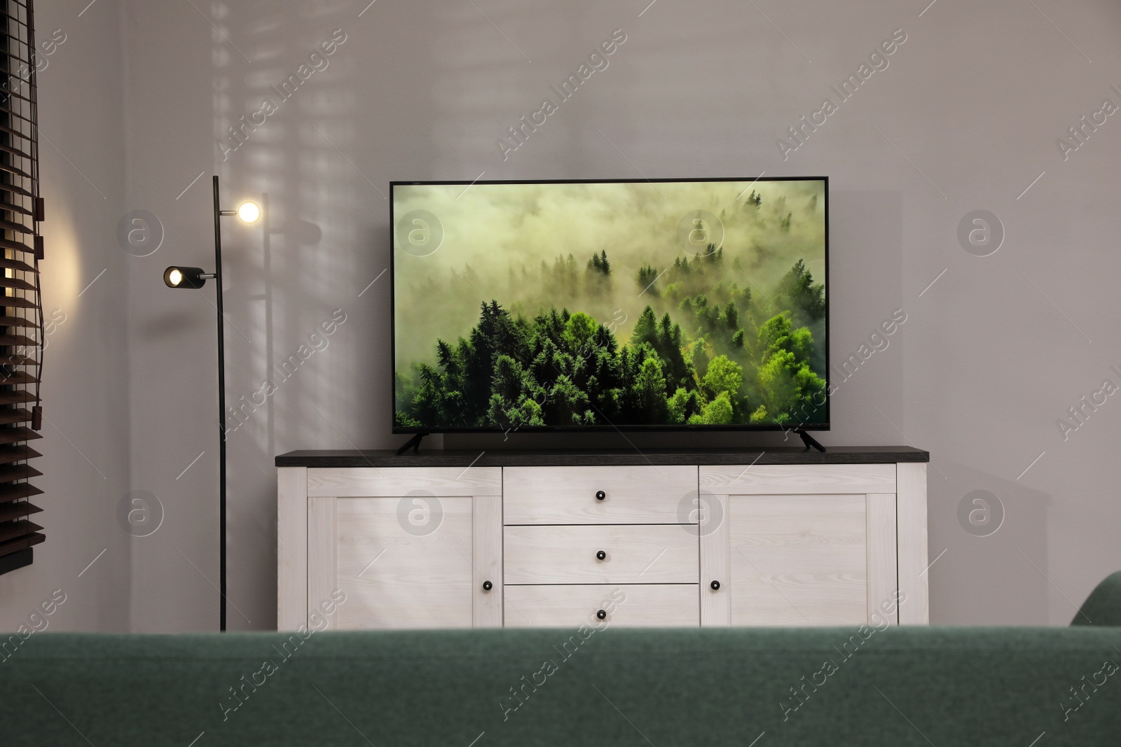 Photo of Modern TV on cabinet near white wall in living room