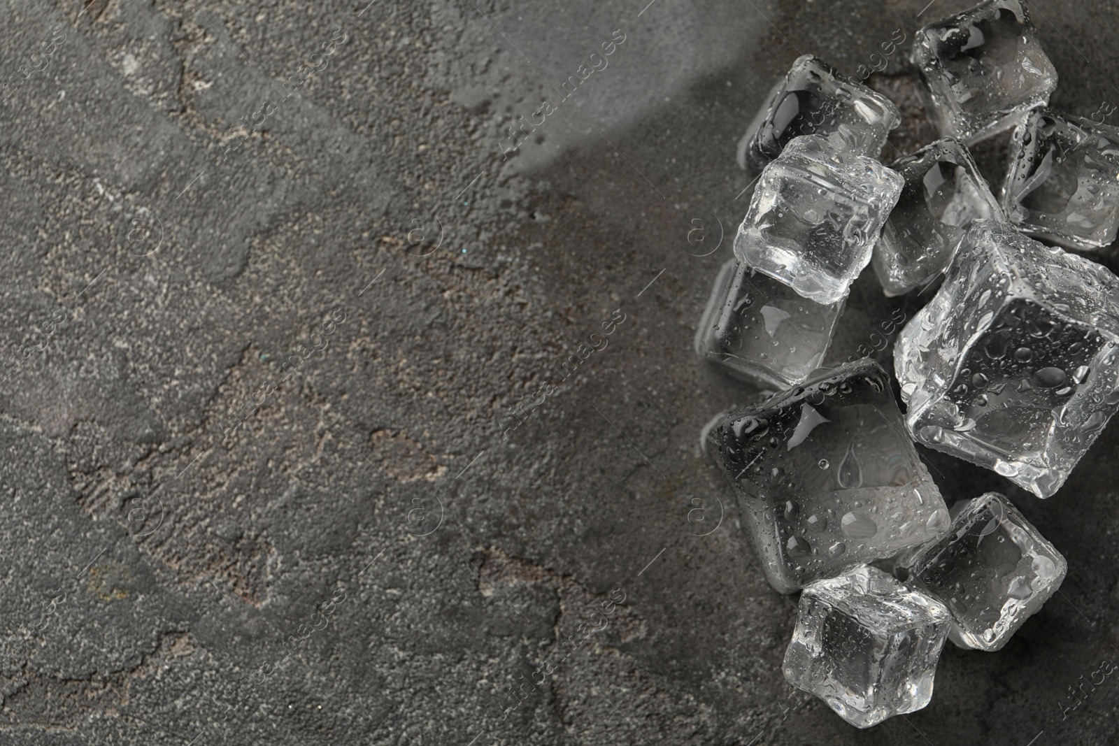 Photo of Crystal clear ice cubes with water drops on grey table, flat lay. Space for text