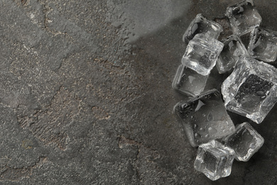 Photo of Crystal clear ice cubes with water drops on grey table, flat lay. Space for text