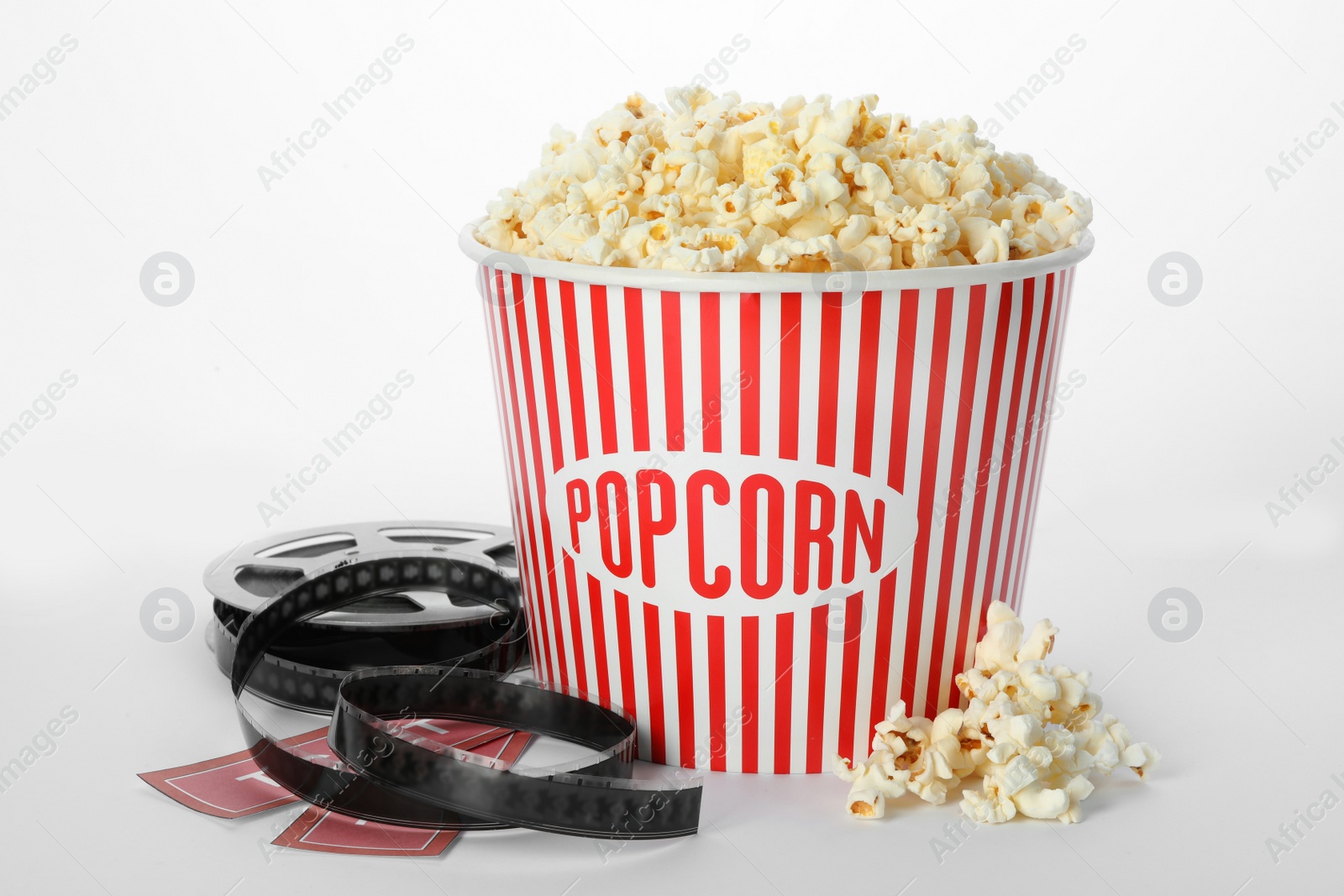 Photo of Bucket of fresh popcorn, tickets and movie reel on white background. Cinema snack