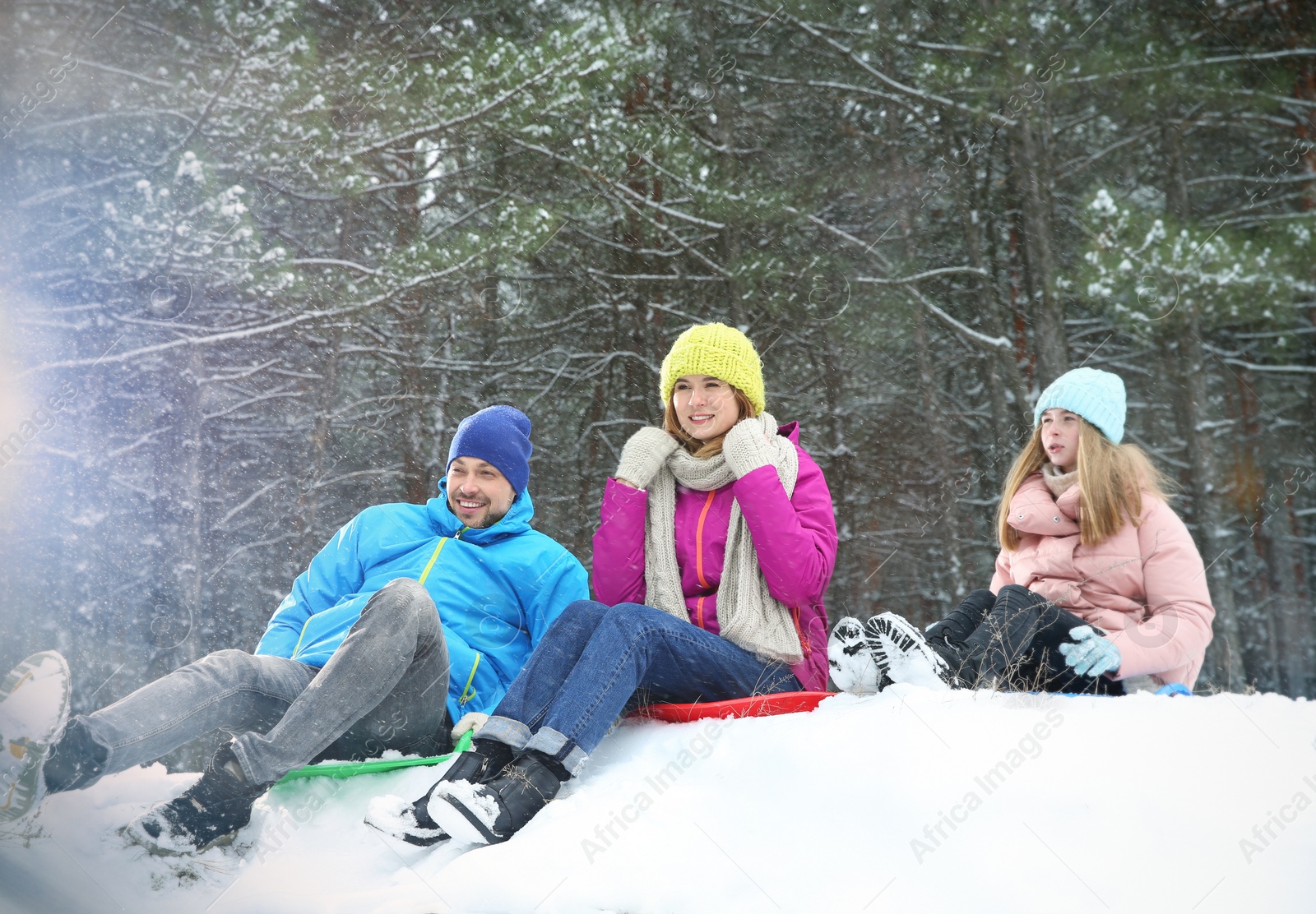 Photo of Happy family sledding in forest on snow day