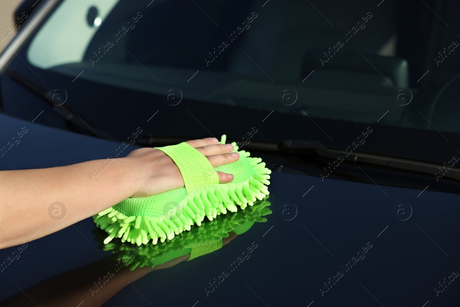 Photo of Man cleaning car hood outdoors, closeup view