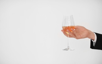 Man holding glass of wine on light background