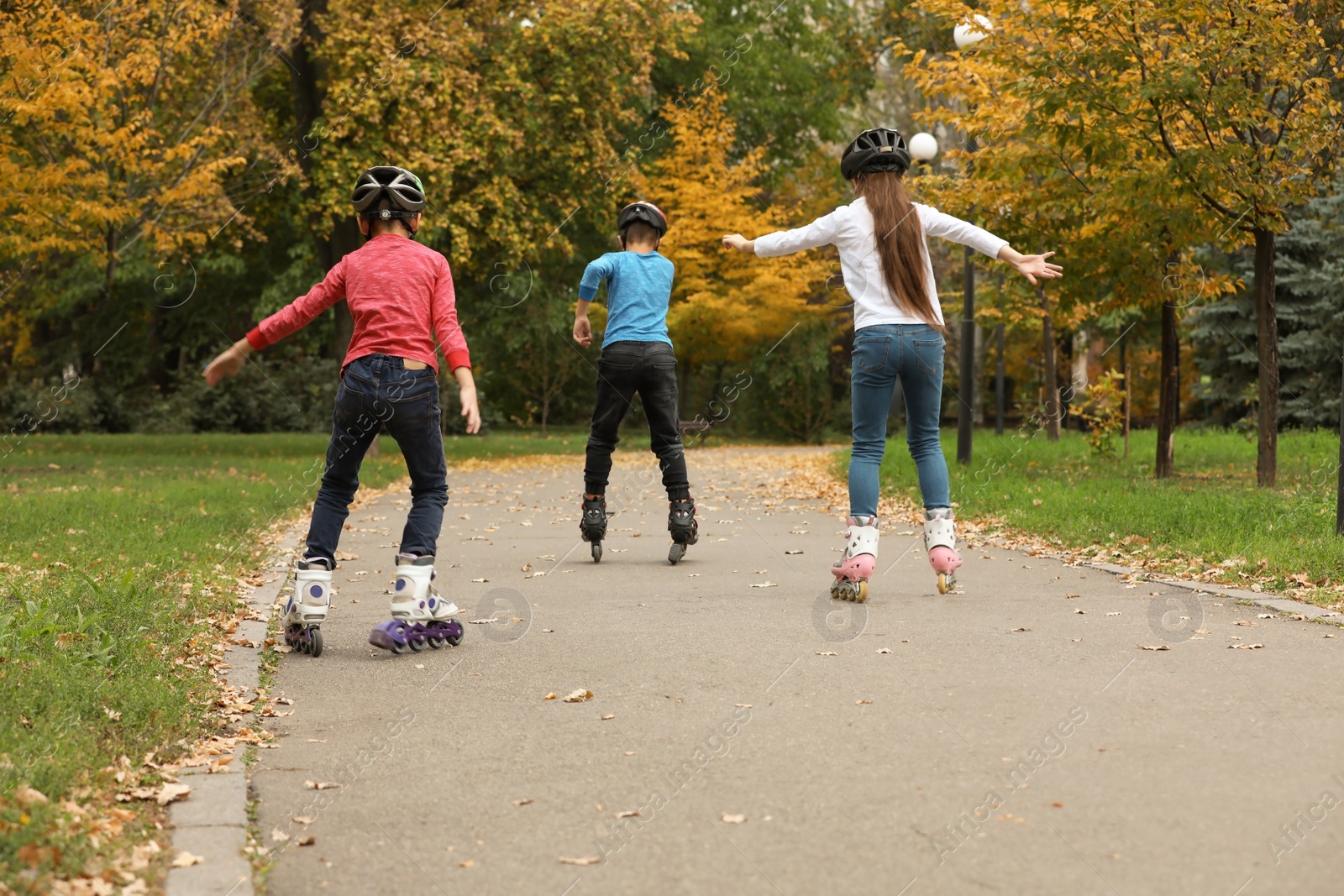 Photo of Cute children roller skating in autumn park