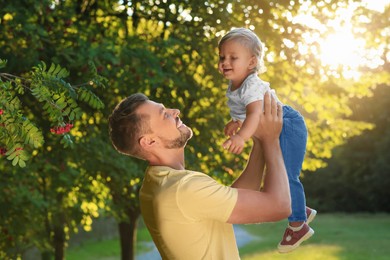 Photo of Happy father playing with his cute baby in park on sunny day
